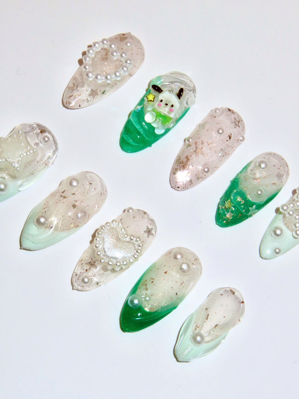 Set of decorative nails with green and beige gradient and embedded pearls on a light background