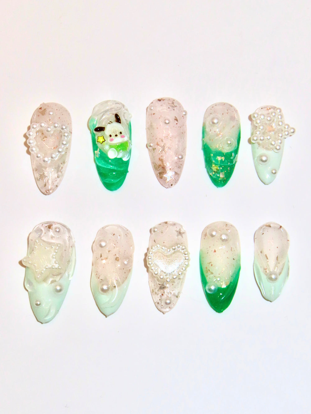 Set of decorative nails with green and beige gradient and embedded pearls on a light background